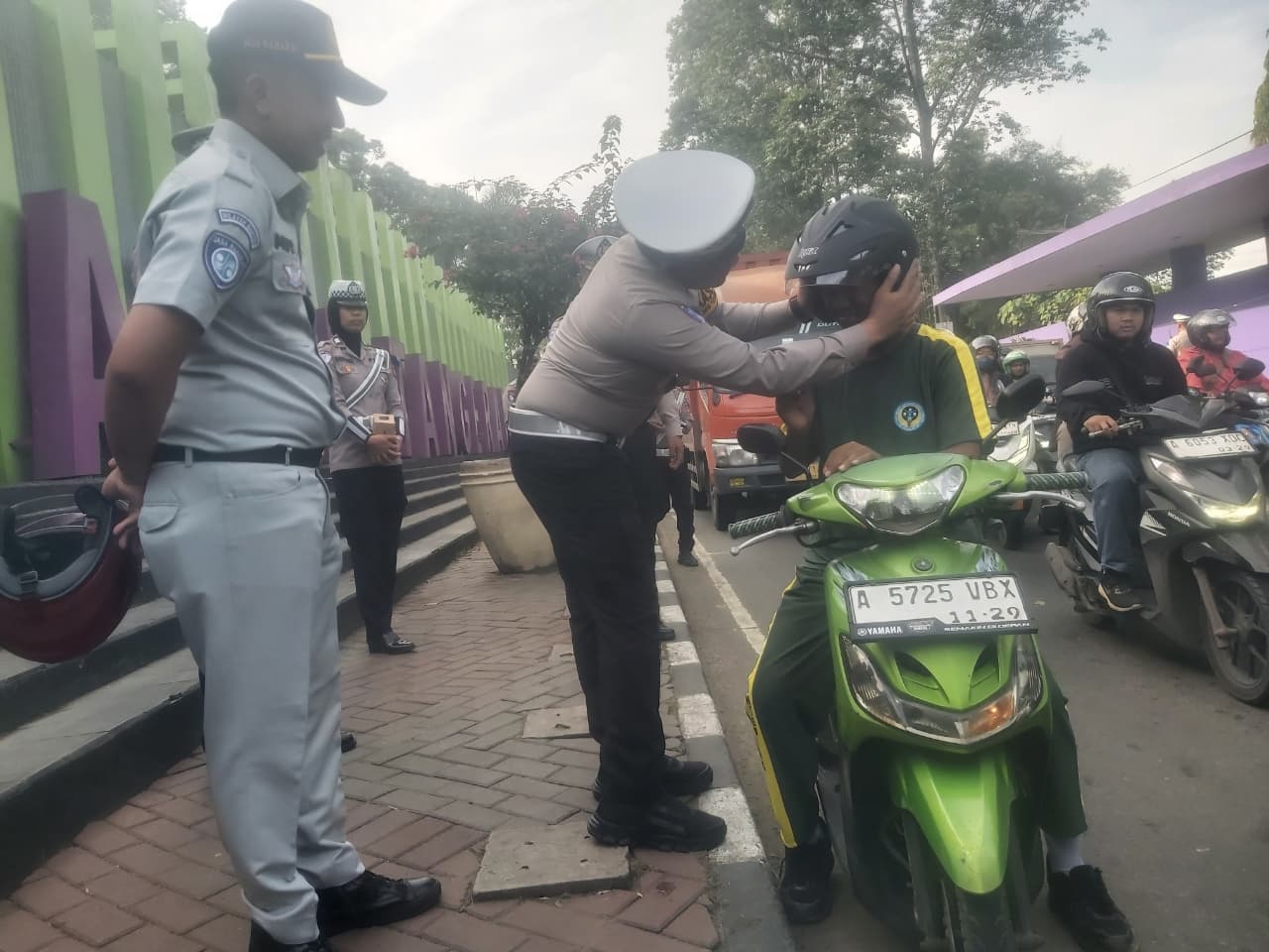 Polisi saat memberikan Helm SNI ke pengendara motor.