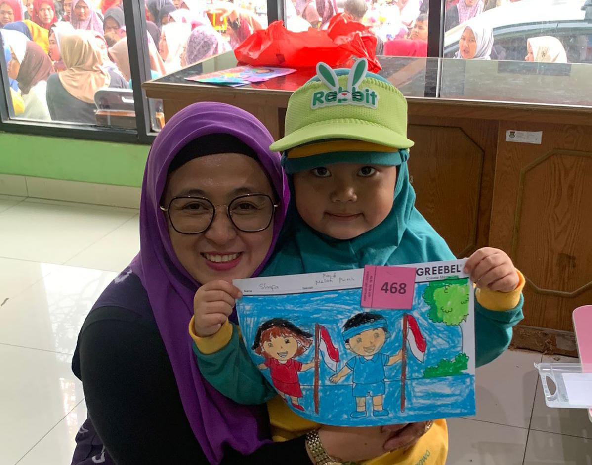 Intan Nurul Hikmah bersama anak -anak yang menunjukan hasil karya lomba mewarnai.