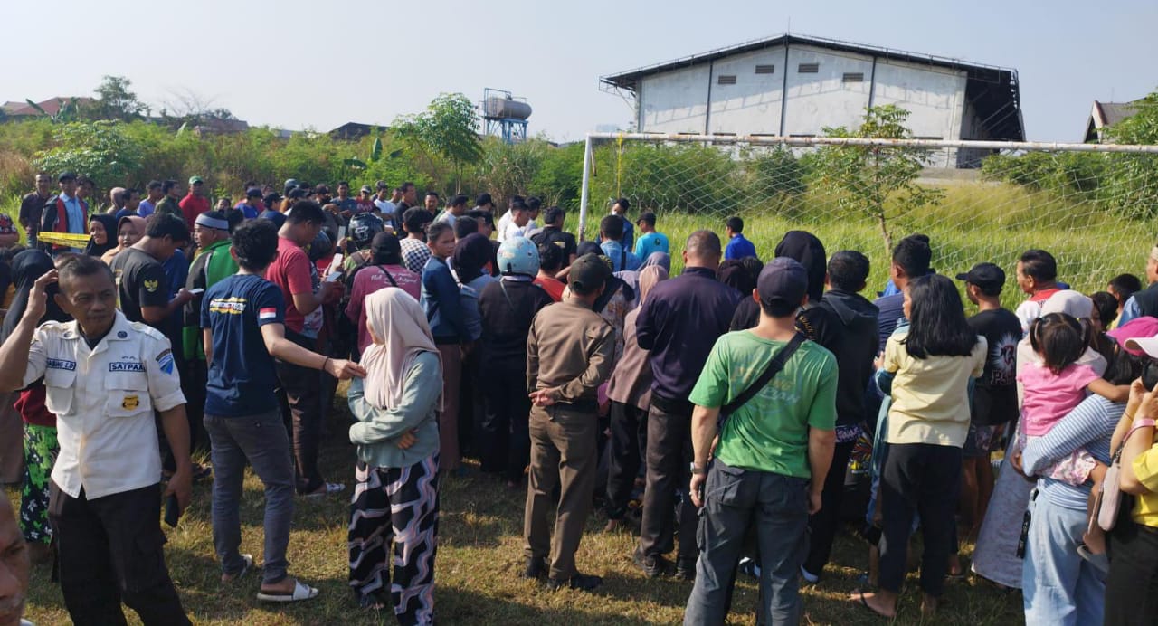 Warga saat melihat polisi mengevakuasi orang yang gantung diri di lapangan sepak bola Jatiuwung.