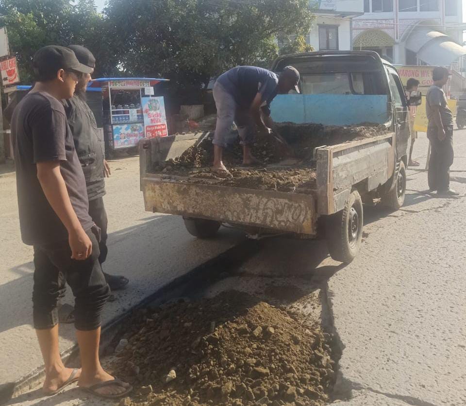 Warga saat swadaya memperbaiki sementara jalan yang berlubang di wilayah Teluknaga.