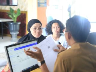 Pegawai Dinas Pendidikan saat membantu warga yang mendaftarkan anaknya sekolah melalui daring.