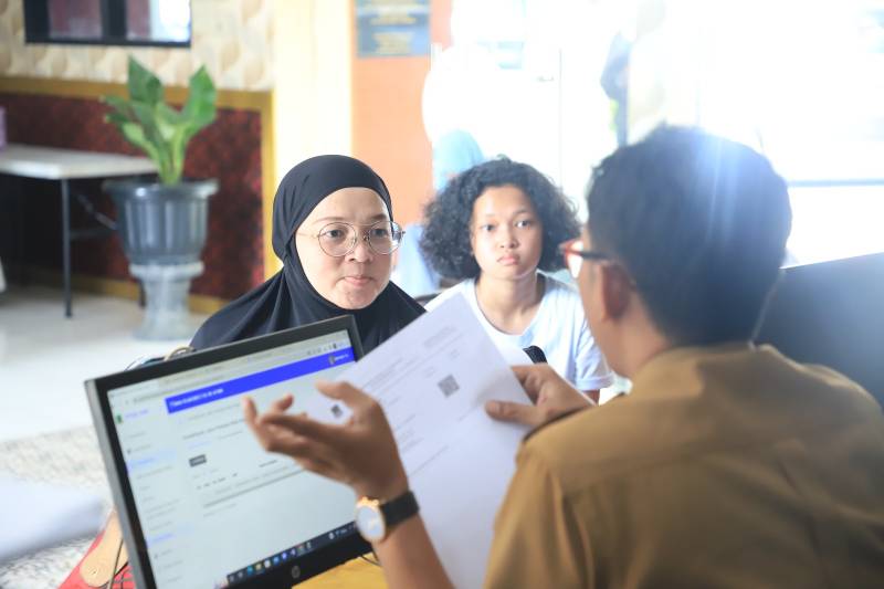 Pegawai Dinas Pendidikan saat membantu warga yang mendaftarkan anaknya sekolah melalui daring.