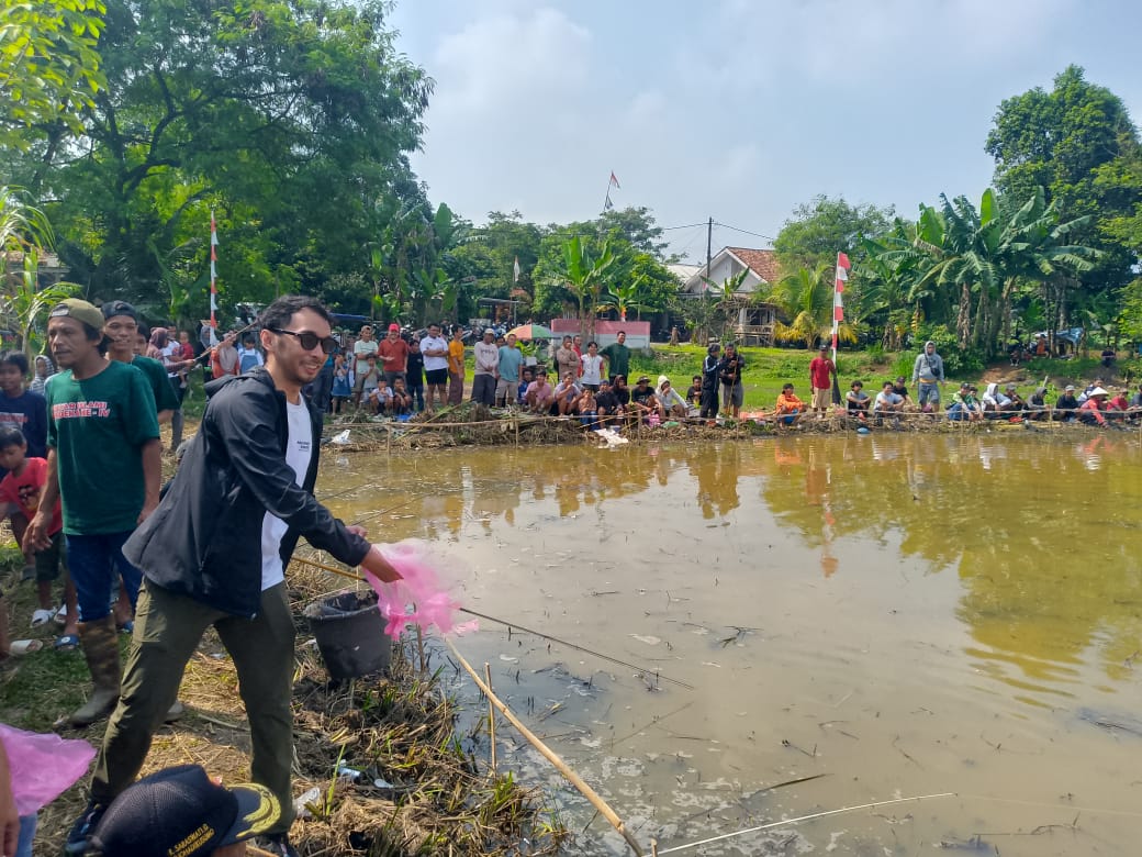 Dewan Iqrar Risyad Nasution saat menyebar ikan.