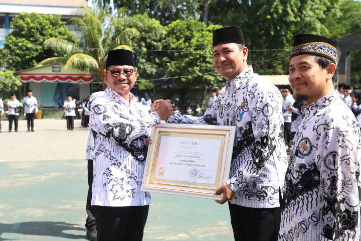 Wali Kota Tangerang Sachrudin (kiri) menyerahkan piagam penghargaan juara umum kepada perwakilan guru Kota Tangerang dari Balai Guru dan Tenaga Kependidikan (BGTK) Banten tahun 2025 di tengah Apel Bersama HUT ke-80 PGRI dan Hari Guru Nasional 2025 di SDN Sukasari 4-5 Kota Tangerang.