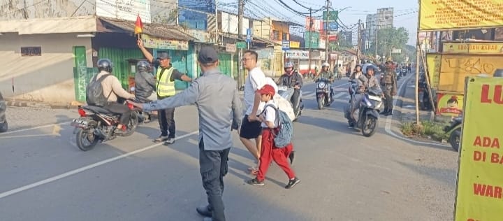 Satlinmas Tangsel saat membantu siswa menyebrang di depan sekolah.