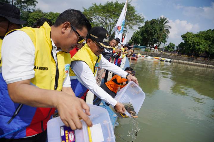 Sachrudin dan Maryono saat menebar benih ikan di sungai Cisadane.